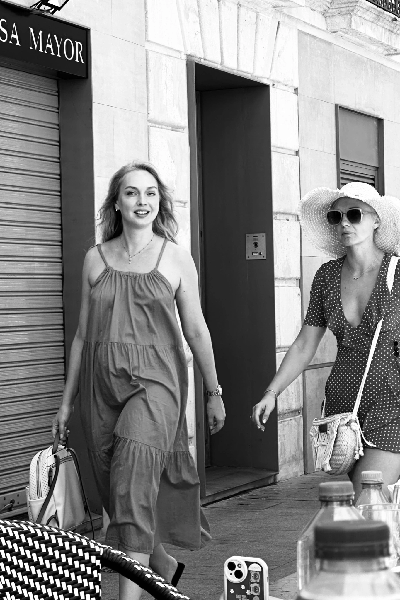 Two women walking past a café in a black-and-white street photograph