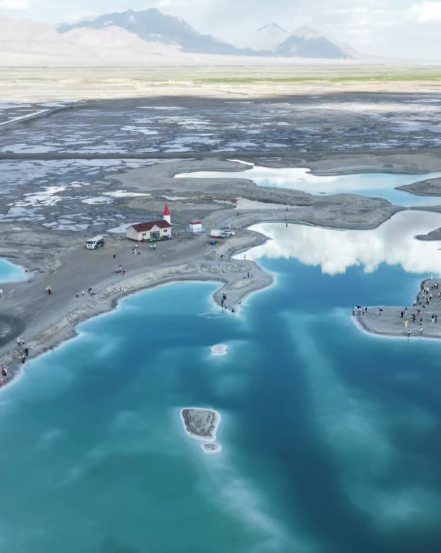 Reflections in mineral pools with small figures and a building on the shoreline